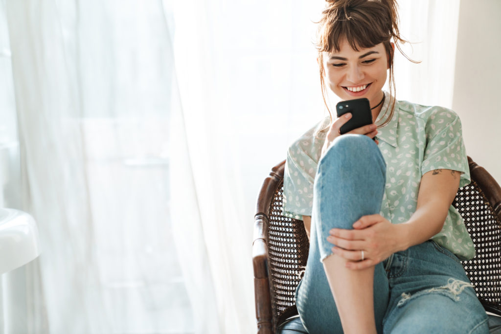 Image of woman sitting in a chair looking at her phone